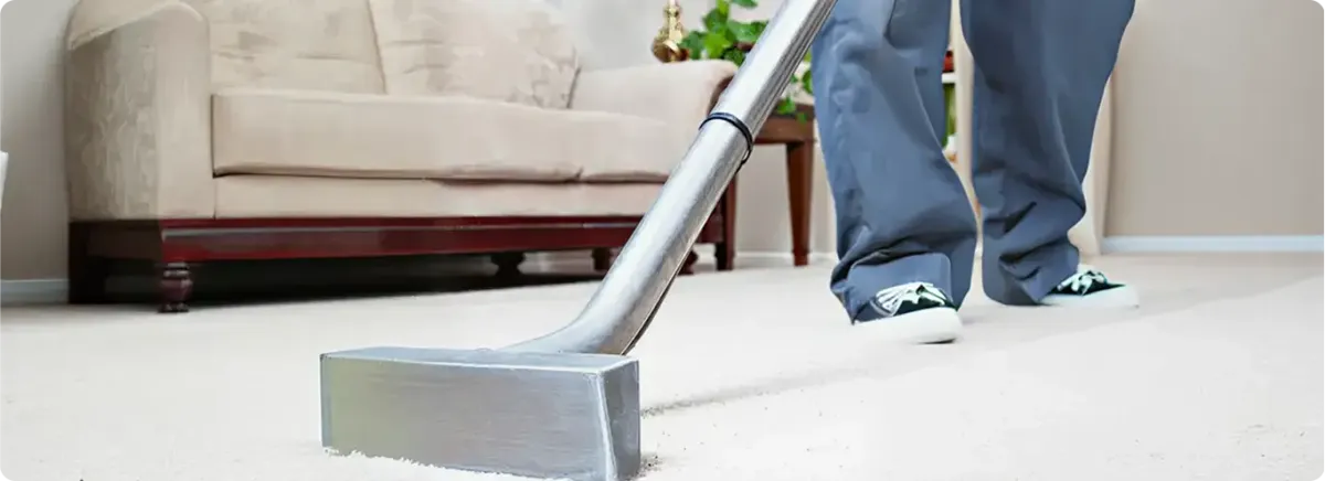 Carpet cleaning technician using a hot-water extraction wand on a light-colored carpet in a living room, Milwaukee, WI.